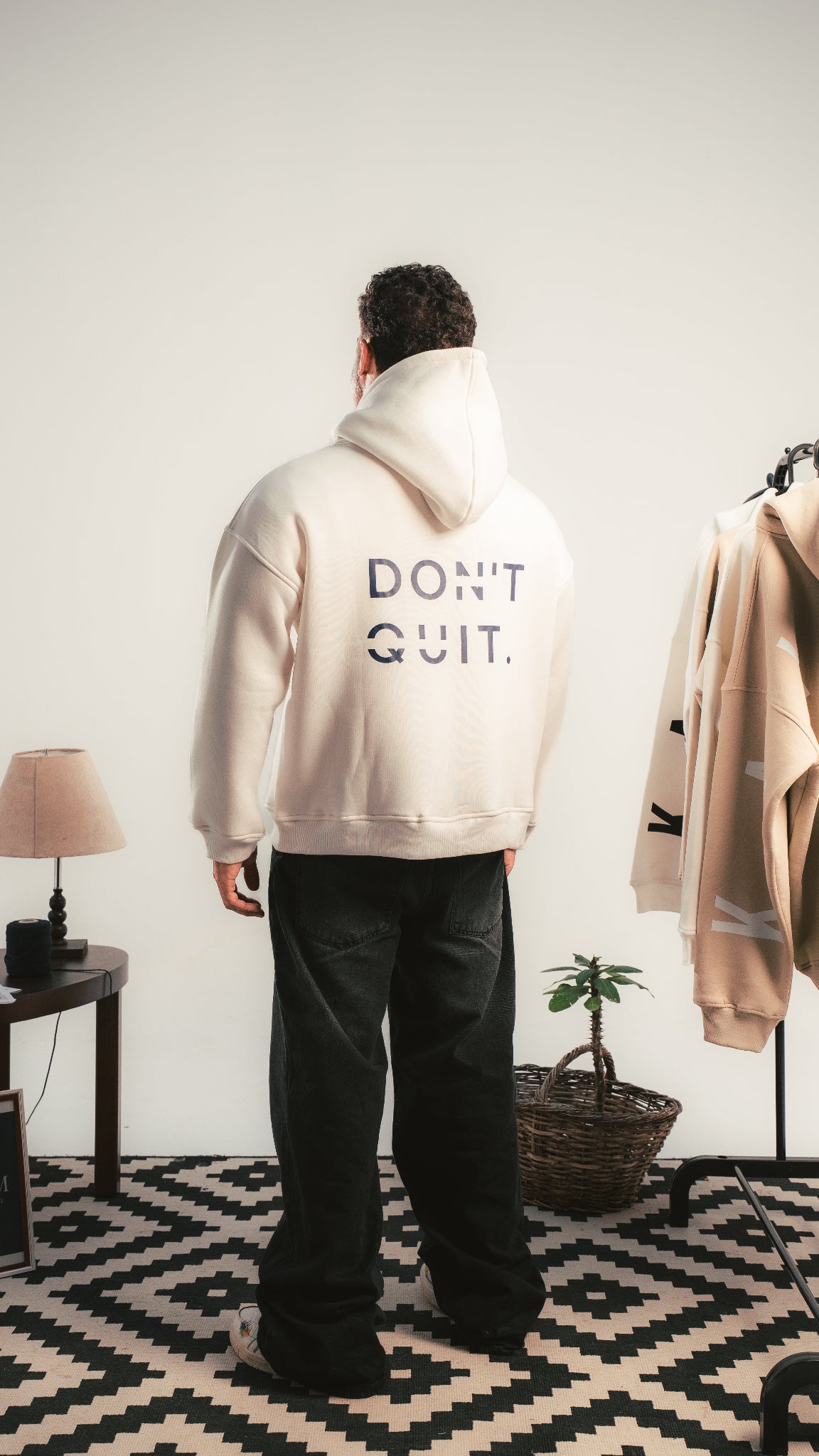 رجل يرتدي هودي DON’T QUIT كريمي من Kalium — خلفية ستوديو بسيطة.