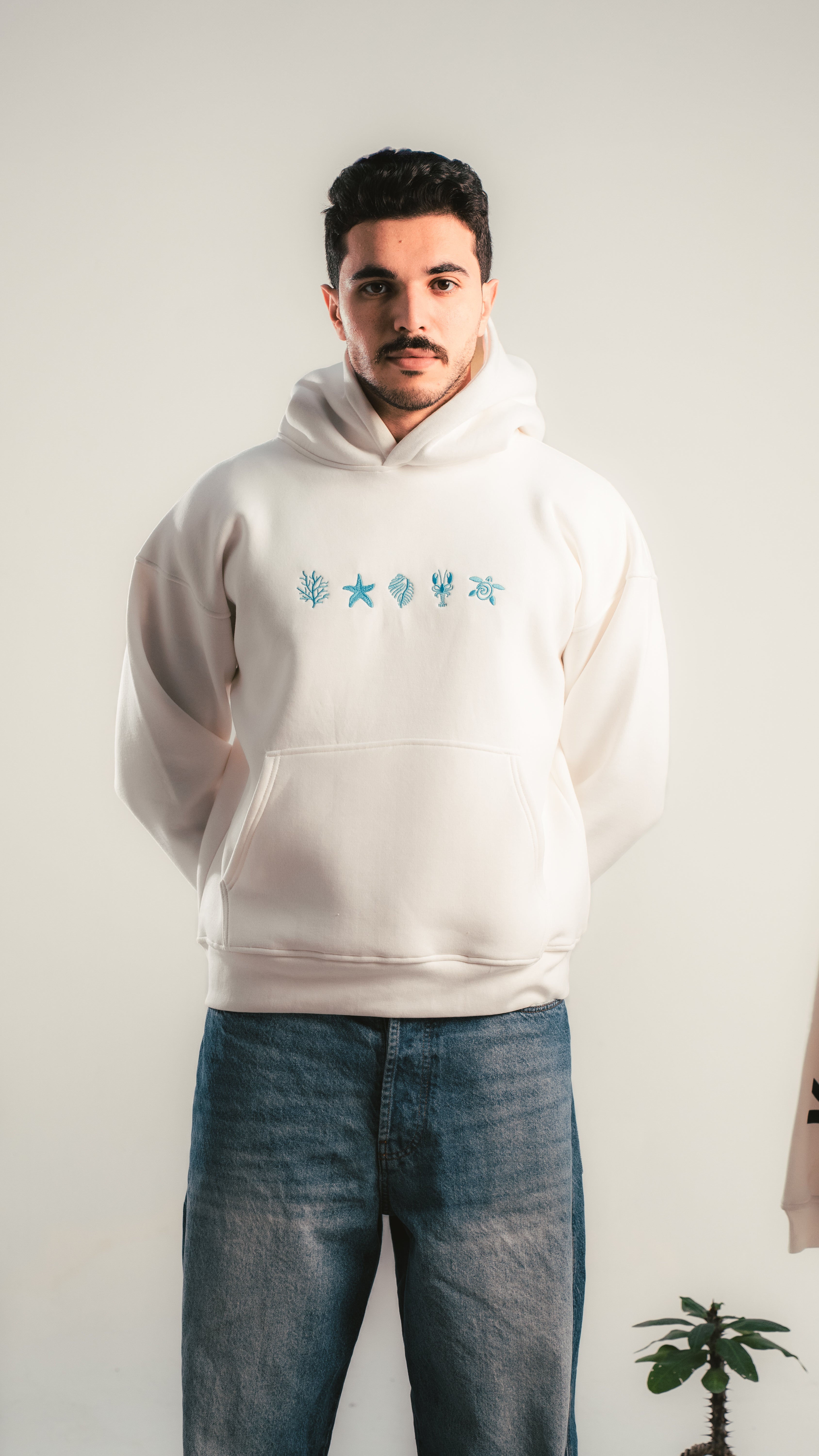 Young man wearing a white oversized hoodie with blue minimal graphics — Kalium