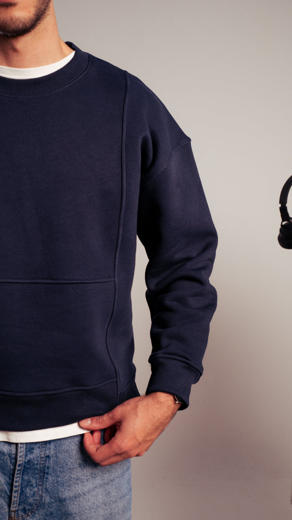 Man wearing navy Kalium sweatshirt with hand in pocket, minimal design.
