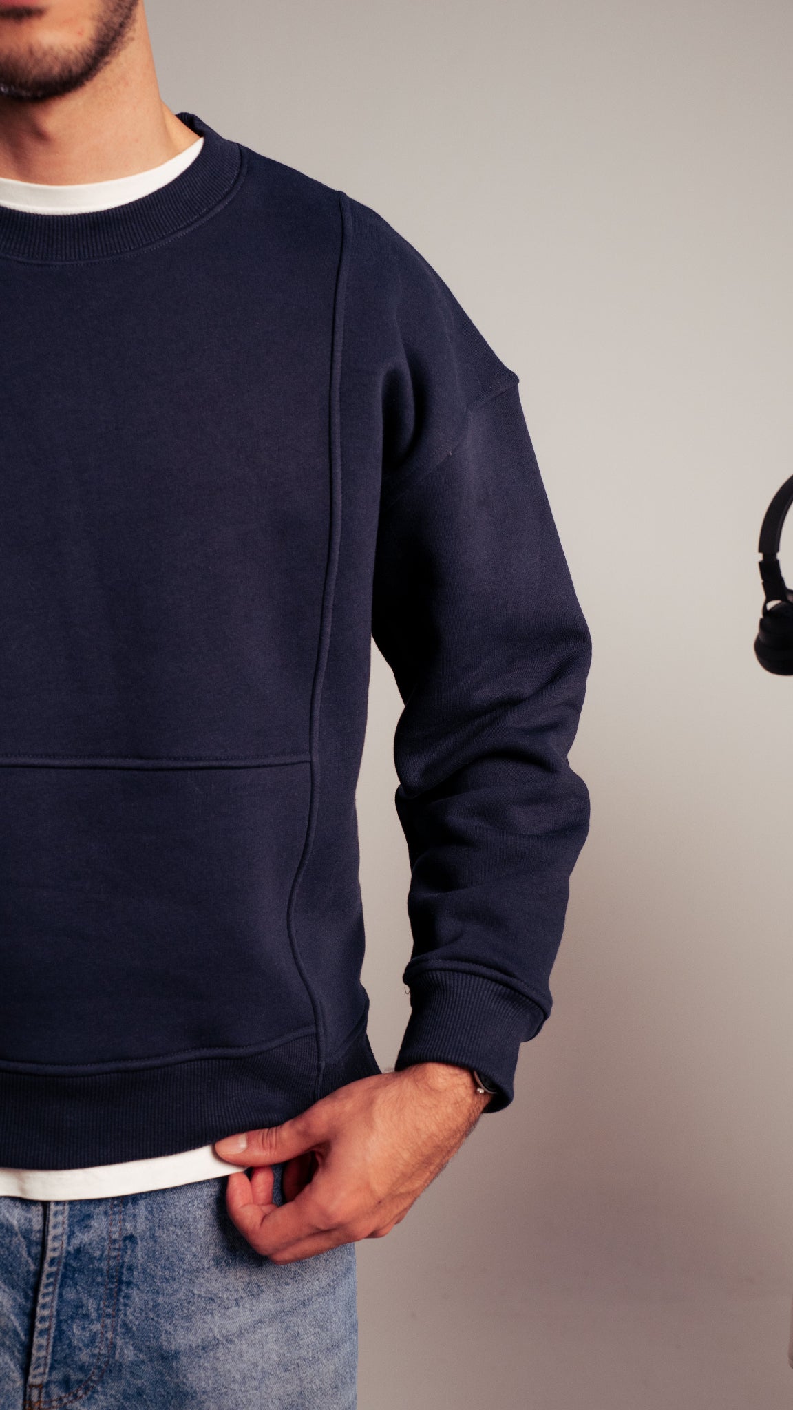 Man wearing navy Kalium sweatshirt with hand in pocket, minimal design.
