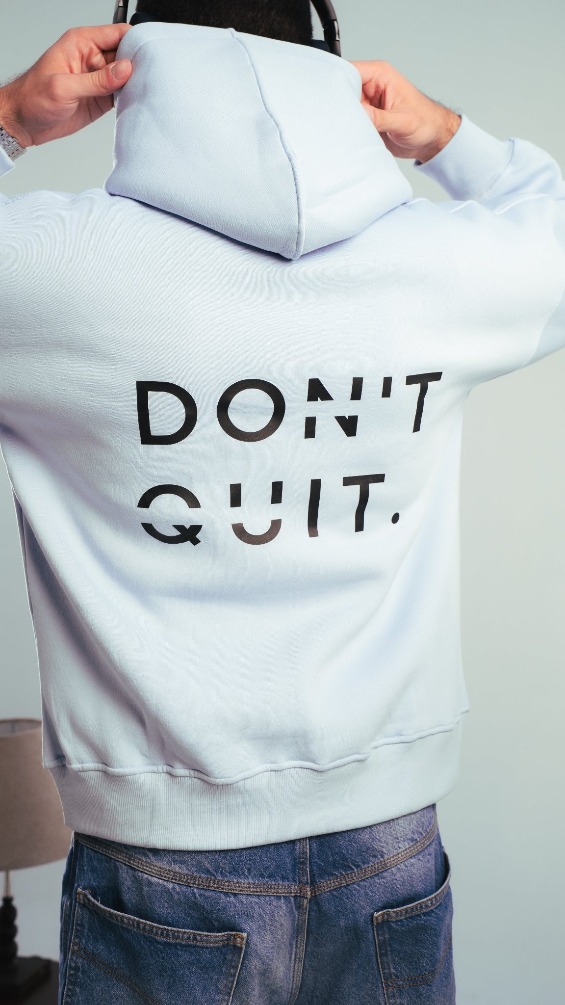شاب يرتدي هودي أزرق فاتح ويقوم بارتداء الكابيشو — تصميم DON’T QUIT — Kalium