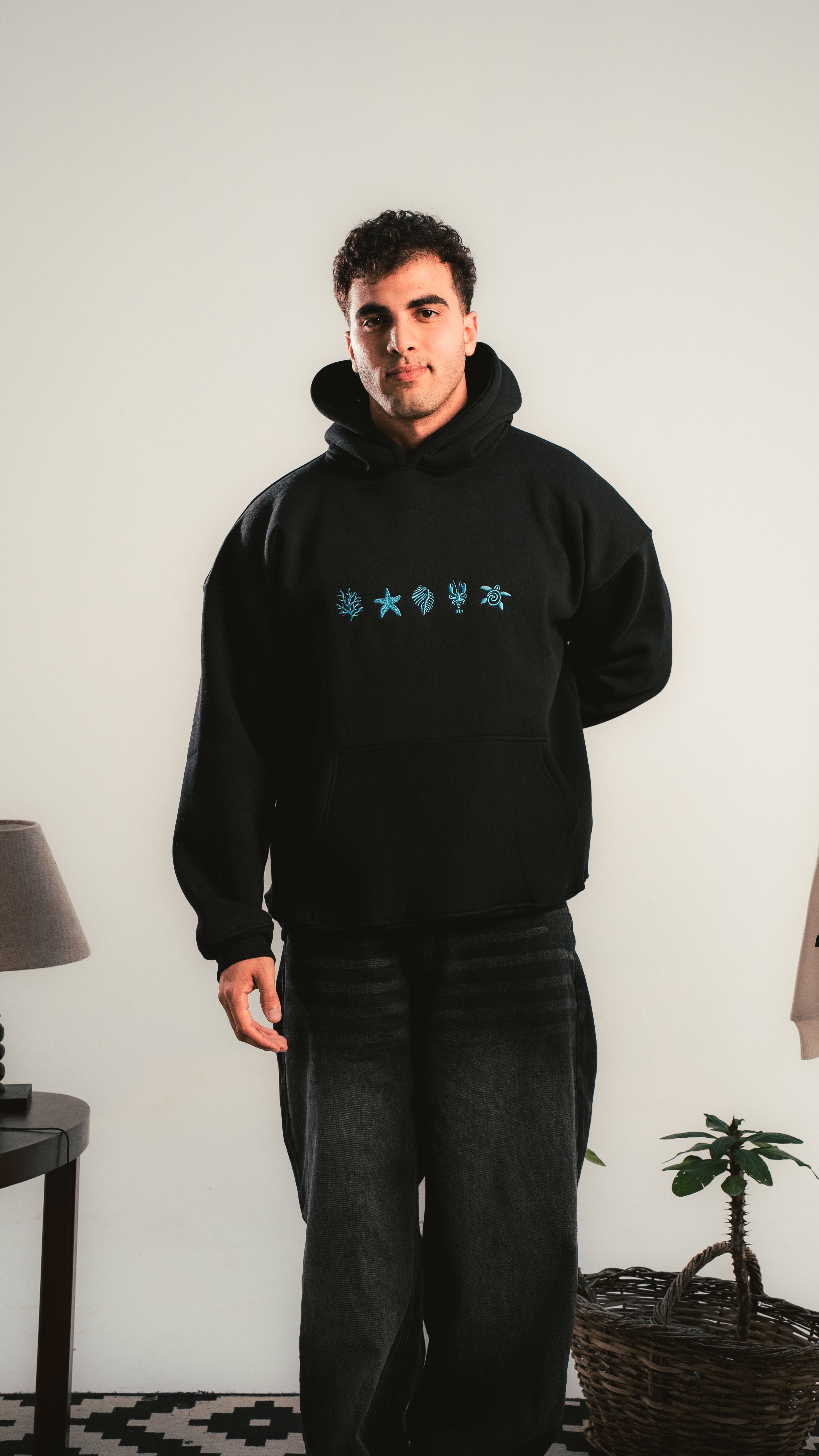 Black oversized hoodie with blue graphic — model standing with skateboard — Kalium