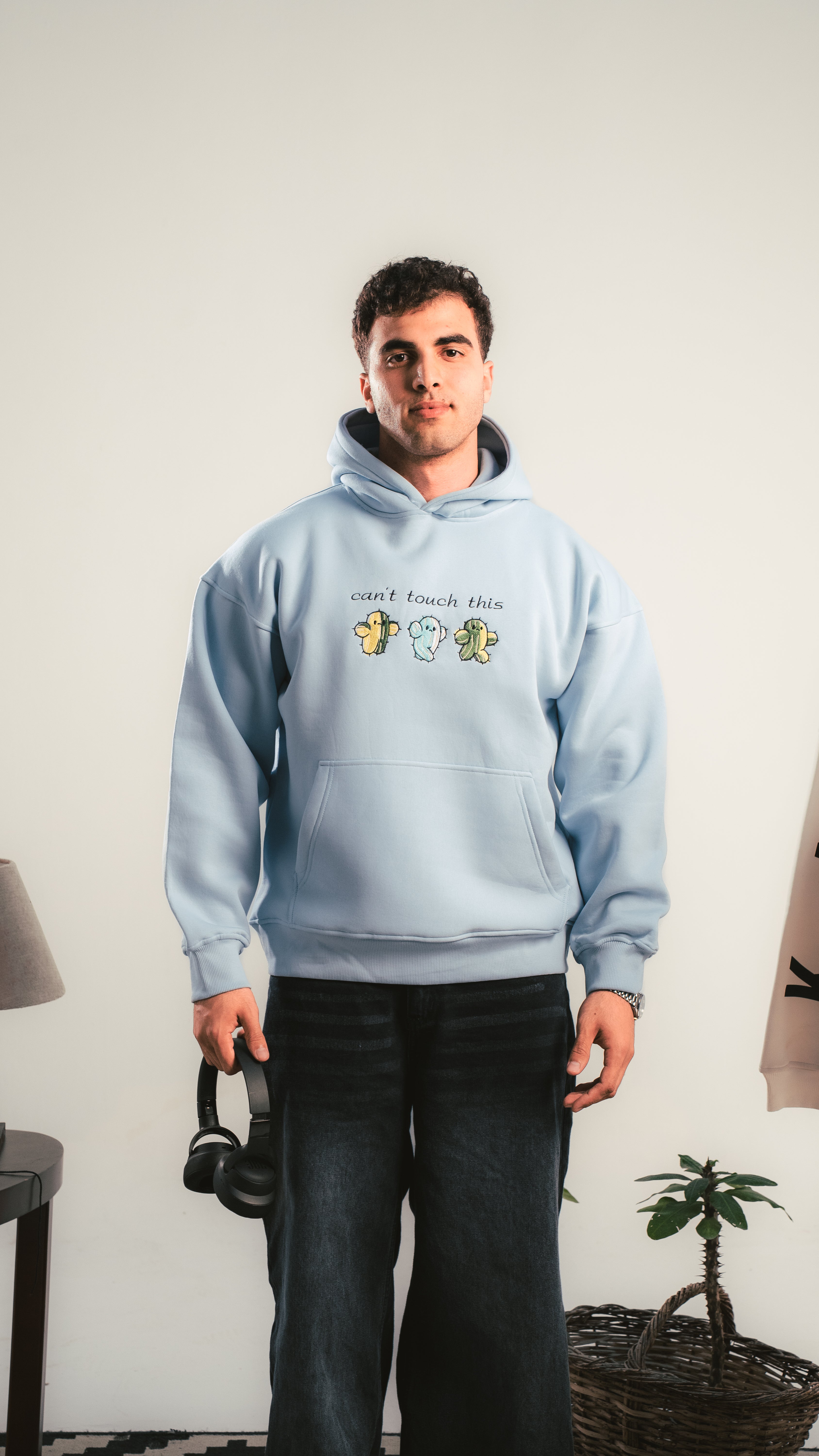 Person wearing a light blue hoodie with text and graphics, standing indoors.