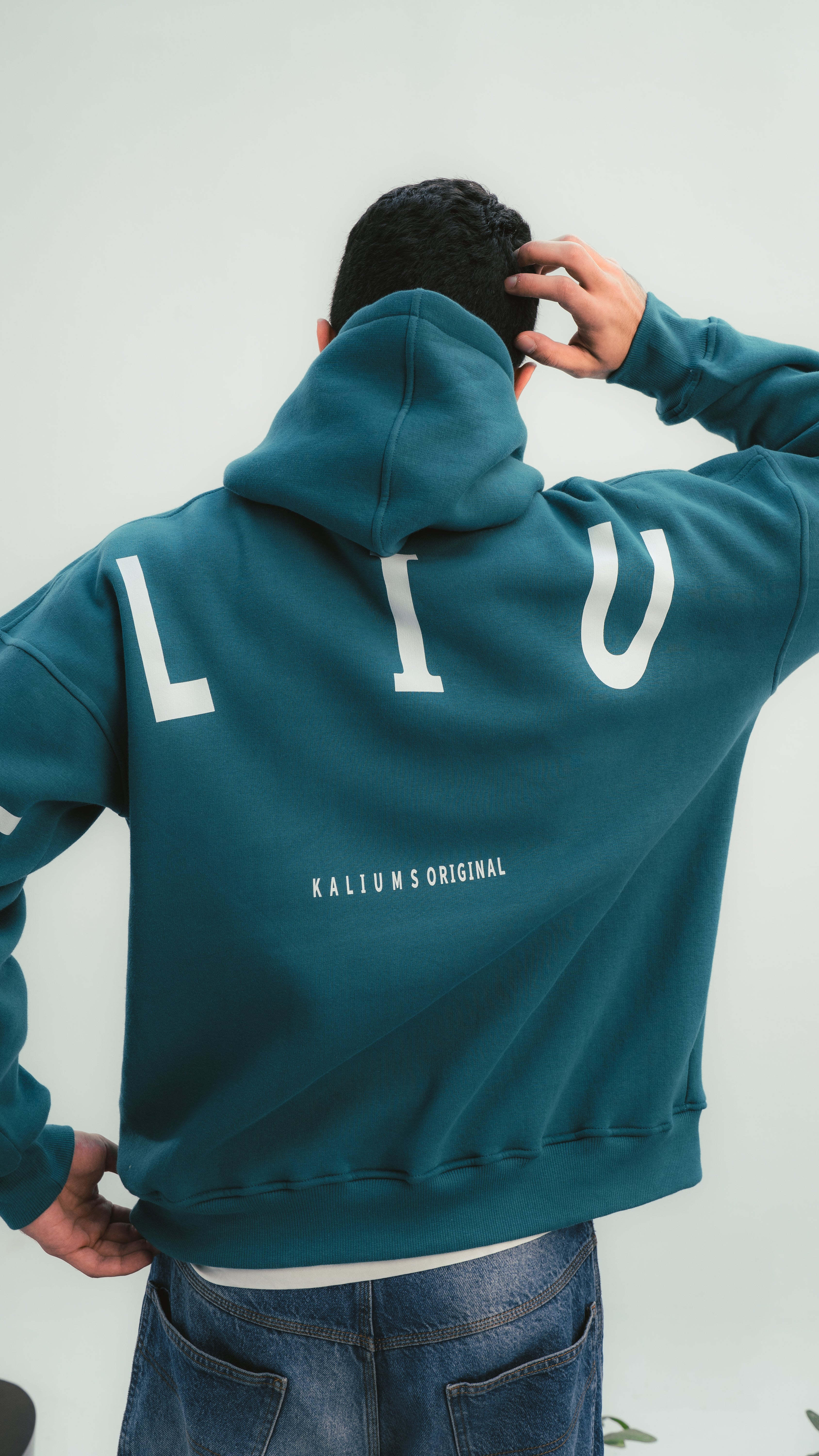 شاب يرتدي هودي أخضر Kalium بتصميم حروف كبيرة من الخلف – لقطة خلفية