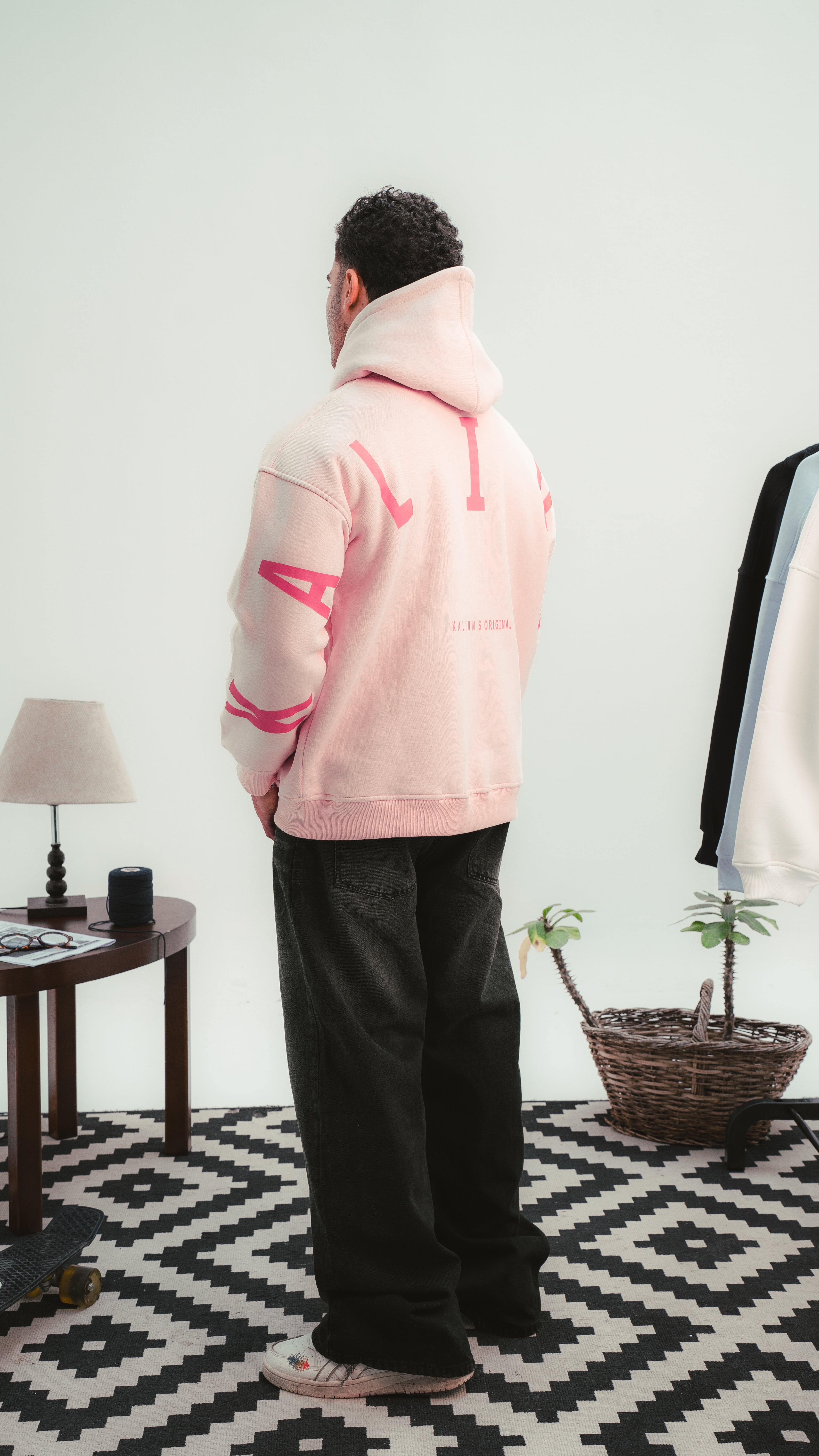 لقطة جانبية لهودي وردي من Kalium بتصميم خلفي بحروف كبيرة مميزة